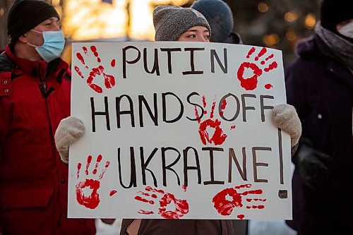 Adelina Krugovykh holds a sign in support of Ukraine in front of Brandon City Hall Friday. (Chelsea Kemp/The Brandon Sun)