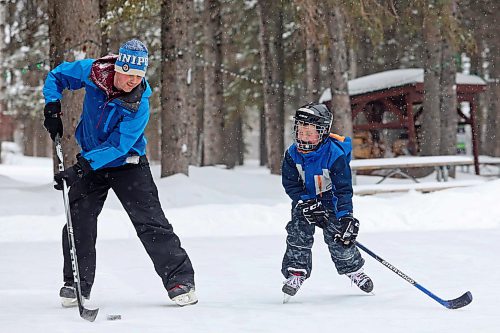 Miles Majcher of Winnipeg, plays shinny with his son Marcus as well as his wife Erin and daughter Rhea on the rink in Wasagaming on a snowy Friday afternoon. (Tim Smith/The Brandon Sun)