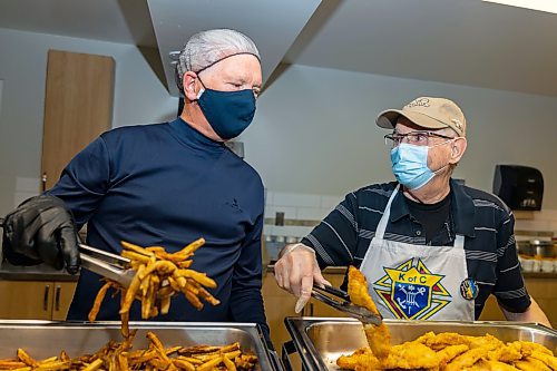 Perry Roque (left) and Bob Denis serve plates of fish and chips for the Knights of Columbus Brandon  council #1435 last fish fry of the season at Augustine Catholic Church Friday. The fry marked the forth of the Lent season. All proceeds raised by the dinner event were donated to the KOFC Ukraine Solidarity Fund. The Knights have raised more than $2,500 over the last month in support of the charity. (Chelsea Kemp/The Brandon Sun)