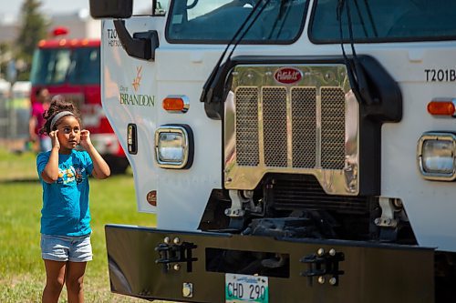 Deborah Diaz, 7, plugs her ears as horns honk during Touch-a-Truck at the Keystone Centre grounds Saturday. (Chelsea Kemp/The Brandon Sun)