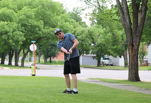 Tyler McDonald practices his chipping on his front lawn on a sunny Tuesday afternoon. (Drew May/The Brandon Sun)