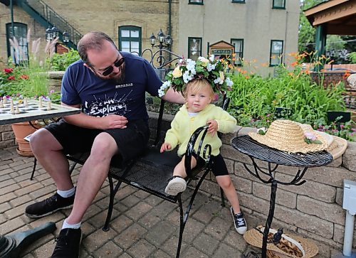 Alex Murray watches his daughter, Maxine, try on a flower hat at the Daly House Museum on Wednesday morning. (Drew May/The Brandon Sun)
