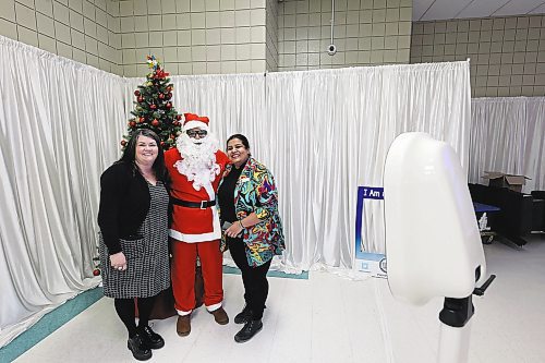 Sarah Ferguson (left) and Archana Krishnan (right) of Westoba Credit Union snap a picture with Santa at a selfie station set up by Trident Films at Thursday's Brandon Chamber of Commerce luncheon. (Colin Slark/The Brandon Sun)