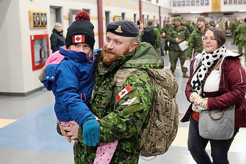 Sgt. Tyler Perry with 1st Regiment, Royal Canadian Horse Artillery, carries his daughter Amelia followed by his wife Madison after he returned to CFB Shilo from Latvia late Thursday night. (Tim Smith/The Brandon Sun)