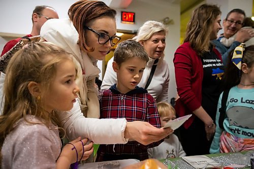 Daniel Crump / Winnipeg Free Press. Angelina Lelisova (middle) her kids Elza Lelisova and Mark Lelisova pick out gifts that they can give to someone else at a Christmas event for recently arrived Ukrainian kids at Oseredok Ukrainian Cultural and Educational Centre. December 10, 2022.