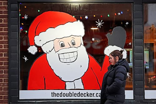 A pedestrian walks past a festive Santa window mural at The Double Decker on 10th Street on Monday. (Tim Smith/The Brandon Sun)