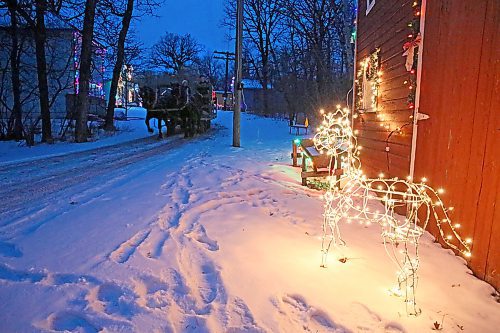 A horse-drawn wagon passes a lit decoration during a tour of the Homesteaders' Village (Ian Hitchen/The Brandon Sun).