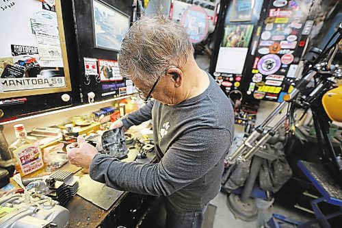 Lex Langston takes a look at a 75cc mini-bike engine being restored on his workbench. Since retiring five years ago, Langston estimates he's restored 10 to 12 motorcycles in his garage. (Colin Slark/The Brandon Sun)