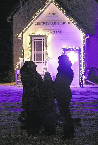 Winter Wonderland visitors are silhouetted in the lights that decorate the Centreville School at the Manitoba Agricultural Museum near Austin. (Ian Hitchen/The Brandon Sun)