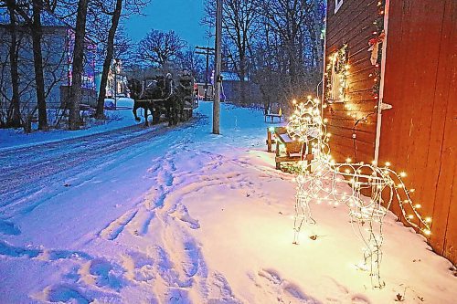 A horse-drawn wagon passes a lit decoration during a tour of the Homesteaders' Village (Ian Hitchen/The Brandon Sun).