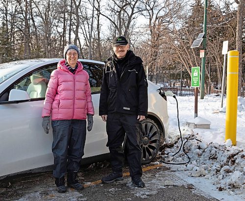 Robert Elms (in black) and his wife, Lois, are photographed with their Tesla at Assiniboine Park on November 21, 2022. (Jessica Lee/Winnipeg Free Press)