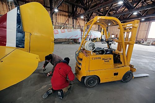 John McNarry (wearing brown) and Art Brown (wearing red) hook up a chain to the tail end of a Bristol Bolingbroke aircraft at the Commonwealth Air Training Plan Museum on Friday. (Colin Slark/The Brandon Sun)