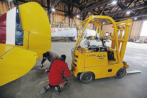 John McNarry (wearing brown) and Art Brown (wearing red) hook up a chain to the tail end of a Bristol Bolingbroke aircraft at the Commonwealth Air Training Plan Museum on Friday. (Colin Slark/The Brandon Sun)