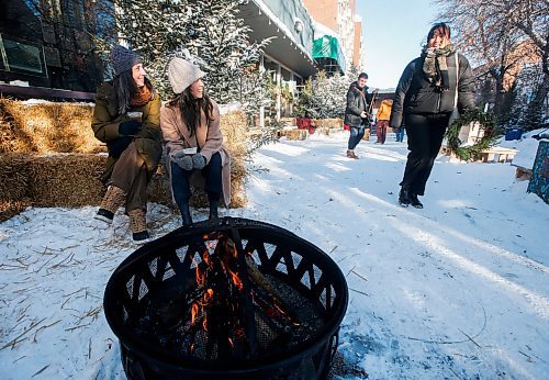 JOHN WOODS / WINNIPEG FREE PRESS
Annick Bernard and Melanie Dupuis, left, enjoy a fire as people walk past at the Winter in the Village festival outside the Gas Station Theatre in Osborne Village Tuesday, November 29, 2022. 

Re: Pische