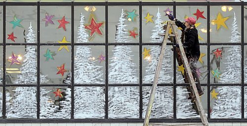 Brandon Sun REACHING FOR THE STARS--Local artist and muralist Anne Boychuk works on a wintery scene on the windows of the Humpty's Restaurant on 18th Street on Monday afternoon. (Bruce Bumstead/Brandon Sun)