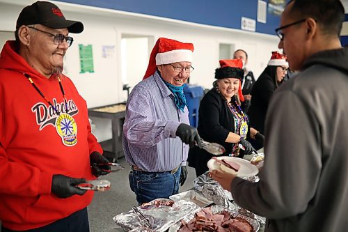 22122022
Sioux Valley Dakota Nation council member Anthony Tacan smiles as he serves community members during the annual Christmas Dinner at the SVDN Veterans Hall on Thursday evening. Sioux Valley also held dinners in Winnipeg and Brandon for members of the First Nation in those cities earlier this month and will hold a final dinner today for community elders. This was the first community Christmas Dinner in three years at Sioux Valley as the dinners for 2020 and 2021 were cancelled due to the COVID-19 pandemic.  (Tim Smith/The Brandon Sun)