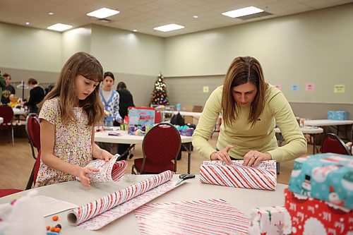 Volunteer Audrey Metruk, 10, wraps presents alongside her mom Lindsay while preparing for the Westman and Area Traditional Christmas Dinner at the Keystone Centre on Friday. (Tim Smith/The Brandon Sun)