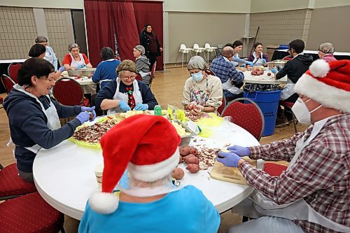 23122022
Paula Stirling, Kim McKee, Gerry Gebhardt (all back of table), Sharon Wiens and her son Stephen Wiens (front in Santa hats) peel and dice potatoes on Friday alongside other volunteers helping prep for the Westman and Area Traditional Christmas Dinner at the Keystone Centre. The dinner runs from noon to 6:00 PM on Christmas day. (Tim Smith/The Brandon Sun)