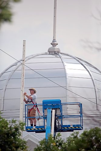 Bob Desjardin, operations manager for the Provincial Exhibition of Manitoba, preps one of the flag poles atop the Display Building No. II (Dome building) for painting. (Matt Goerzen/The Brandon Sun)