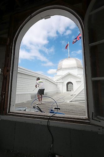 Painter Brayan Webber with Malereii Painting, seen here through a window of one of the four domes, adds another coat of white paint to the roof portion of the Display Building No. II, otherwise known as the Dome Building. (Matt Goerzen/The Brandon Sun)