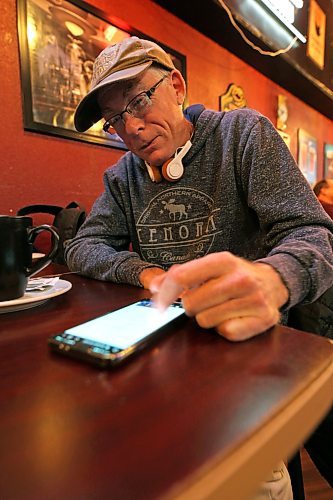 Brandon mayoral candidate Elliott Oleson watches results from the 2022 municipal election crawl in on his phone while out with friends at the Guiness Tavern on Rosser Avenue on election night. (Matt Goerzen/The Brandon Sun)