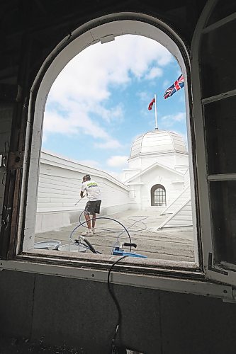 Brandon Sun Painter Brayan Webber with Malereii Painting, seen here through a window of one of the four domes, adds another coat of white paint to the roof portion of the Display Building No. II, otherwise known as the Dome Building, on Friday afternoon. (Matt Goerzen/The Brandon Sun)