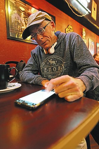 Brandon mayoral candidate Elliott Oleson watches results from the 2022 municipal election crawl in on his phone while out with friends at the Guiness Tavern on Rosser Avenue on Wednesday evening. (Matt Goerzen/The Brandon Sun)