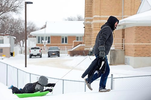 Jason Hlady pulls his four-year-old son up the hill at Rideau Park in a sled while the two toboggan together on an overcast Friday afternoon. (Tim Smith/The Brandon Sun)