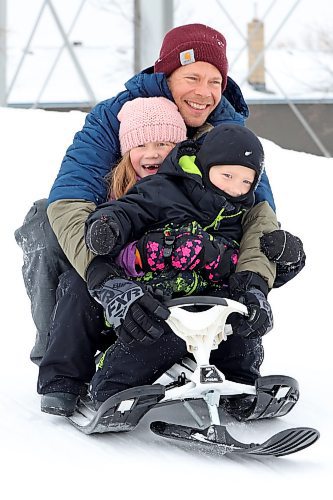 Kevin Roberts and his children Asher (front) and Addison (middle) slide down the hill at Rideau Park in Brandon together on an overcast Friday afternoon. (Tim Smith/The Brandon Sun)