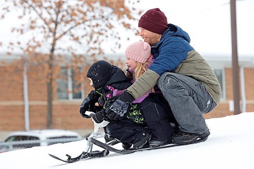 30122022
Kevin Roberts (R) and his children Asher (L) and Addison (C) slide down the hill at Rideau Park in Brandon together on an overcast Friday afternoon. (Tim Smith/The Brandon Sun)