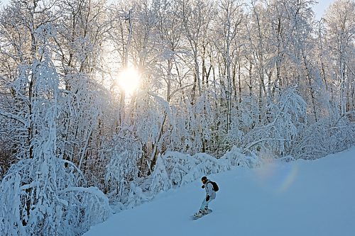 A snowboarder makes their way down a run as the sun shines through hoar frost covered trees at Asessippi Ski Resort on Tuesday. (Tim Smith/The Brandon Sun)