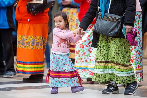 MIKE DEAL / WINNIPEG FREE PRESS
Wabigwan Greene, almost 3-yrs-old, holds her grandmother's hand during the first National Ribbon Skirt Day event at the Polo Park Shopping Centre on Wednesday. National Ribbon Skirt Day is held on January 4th a day where Indigenous women across the country are encouraged to wear their traditional regalia to celebrate their culture, their strength and their connection as women.
230104 - Wednesday, January 04, 2023.