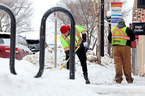 Workers clear snow in front of businesses on 10th Street between Rosser and Princess avenues in Brandon on Wednesday. (Tim Smith/The Brandon Sun)