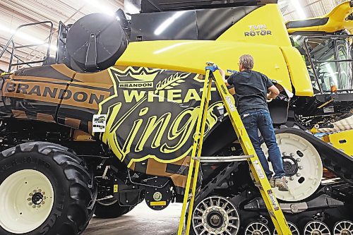 16012023
Owner Al Grebinski with Accent Striping and Lettering affixes a Brandon Wheat Kings wrap to a New Holland combine at the Keystone Centre on Monday in preparation for Manitoba Ag Days 2023, which begins today. 
(Tim Smith/The Brandon Sun)