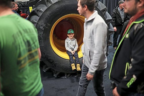 Five-year-old Jackson Siemens of Morris sits in the tire well of a Versatile tractor during Manitoba Ag Days at the Keystone Centre on Tuesday. (Tim Smith/The Brandon Sun)