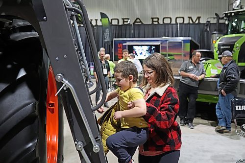 18012023
Four-and-a-half-year-old McKinnley Waldner gets help up the ladder of a combine by his mom Kayla during Manitoba Ag Days 2023 at the Keystone Centre on Wednesday.  (Tim Smith/The Brandon Sun)