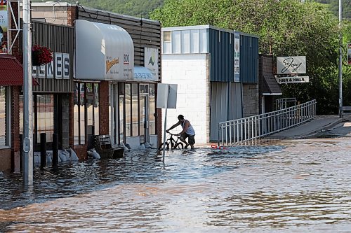 Jesse Hunt walks his bike through flood water inundating Main Street in Minnedosa during June 2020, when the swollen Little Saskatchewan River overflowed into downtown Minnedosa flooding several businesses and residences. Work on the pedestrian bridge located at First Avenue Southwest is well underway, being one of the final major projects in completing the Disaster Financial Assistance claim from the 2020 flood. (Tim Smith/The Brandon Sun)