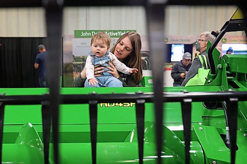19012023
Eight-year-old Emma Dube checks out a John Deere combine header while held by her mother Sabrina during Manitoba Ag Days 2023 on Thursday.
(Tim Smith/The Brandon Sun)