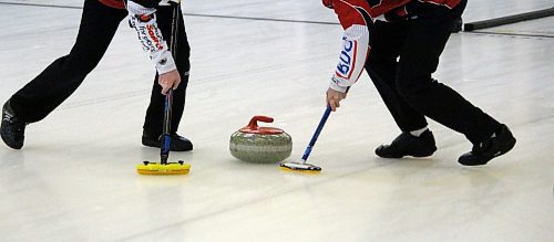 Lead Brogan Schneider, left, and third Ethan Marshall of Jack Lyburn's Brandon rink sweep a rock that was thrown by second Rylan Campbell on Thursday night during the junior provincial playdowns at the Brandon Curling Club. (Lucas Punkari/The Brandon Sun)