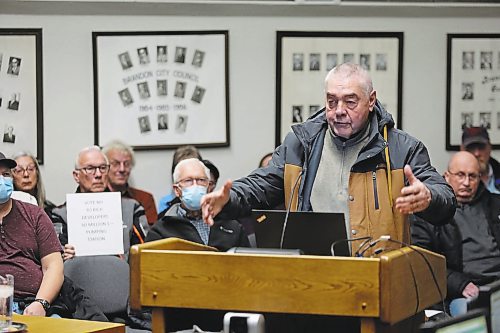 A member of the public speaks in opposition to the southwest lift station project's $30 million debenture as another holds up a sign expressing a similar viewpoint at Monday's second public hearing for the loan. (Colin Slark/The Brandon Sun)