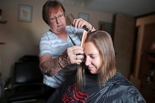 23012023
Iris Karton cuts and styles her daughter Meigan Oakley's hair after cutting off Oakley's 19 inch braid of hair in Oakley's basement hair studio on Monday afternoon. Oakley has been growing her hair for 10 years and will donate the hair to Wigs For Kids. She also donated her hair to the same organization a decade ago. (Tim Smith/The Brandon Sun)