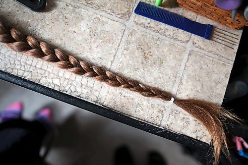 23012023
Meigan Oakley's braid of hair sits on a table after Oakley's mom Iris Karton cut it off in Oakley's basement hair studio on Monday afternoon. Oakley has been growing her hair for 10 years and will donate the hair to Wigs For Kids. She also donated her hair to the same organization a decade ago. The hair in the braid was approximately 19 inches long. 
(Tim Smith/The Brandon Sun)