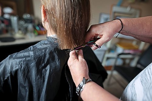 Iris Karton cuts a 19-inch braid of hair off her daughter Meigan Oakley in Oakley's basement hair studio onMonday afternoon. (Tim Smith/The Brandon Sun)