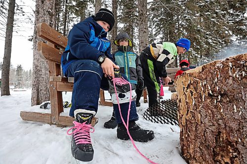 25012023
Zander Plett ties his ice skates as his dad Ty builds a fire so Zander and his siblings can roast hotdogs during a day of adventure in Wasagaming at Riding Mountain National Park on a mild Wednesday afternoon. 
(Tim Smith/The Brandon Sun)