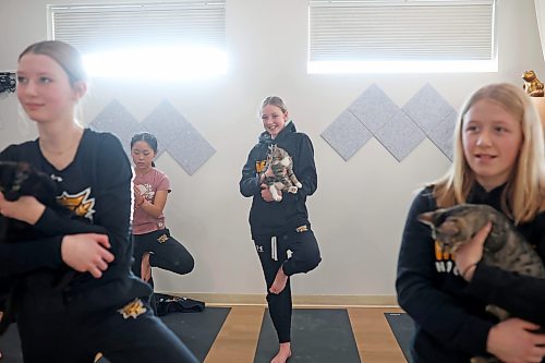 30012023
Paige Thompson (C) smiles while holding a kitten and taking part in a yoga glass with teammates from her U13 AA female Wheat Kings team during Caturday kitten yoga at Luna Muna yoga and wellness studio in Brandon on Saturday. 
(Tim Smith/The Brandon Sun)
