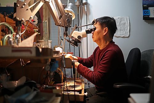 Dat Tao, owner of TCM Goldsmith on Rosser Avenue in downtown Brandon, peers through a magnifier while repairing a ring in his workshop. (Tim Smith/The Brandon Sun)
