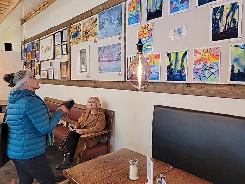Donna Huck admires art created by Touchwood Park's day program students at Brews Brothers Bistro in Neepawa on Feb. 8. (Miranda Leybourne/The Brandon Sun)
