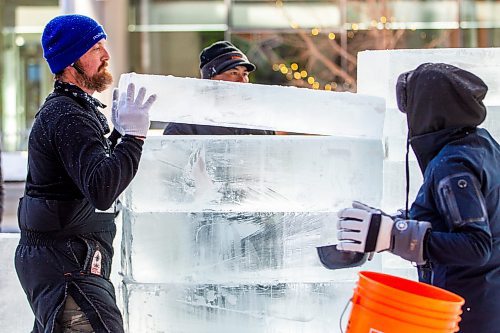 Nate McKeough (left) stacks ice blocks as Anna Sandova adds water between the layers in preparation for ice carving at True North Square on Tuesday. (Winnipeg Free Press)