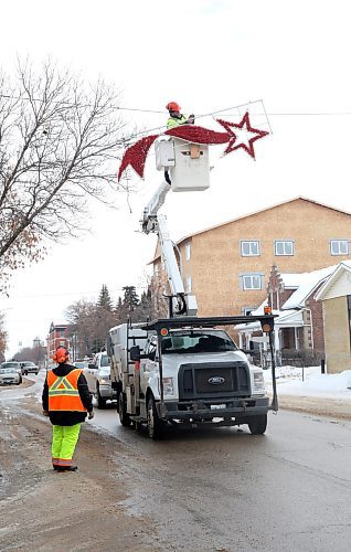 Mike Hutch, a trades worker with the City of Brandon's parks department, begins to remove one of a pair of shooting star Christmas decorations along Princess Avenue on Wednesday morning. According to City of Brandon parks department employee Ryan Savage, seen standing on the ground near the truck, this was the very last set of holiday decorations to be removed for the season. (Matt Goerzen/The Brandon Sun)