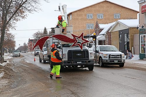 Mike Hutch, a trades worker with the City of Brandon's parks department, hands one of a pair of shooting star Christmas decorations to fellow parks department employee Ryan Savage while at their last stop along Princess Avenue on Monday morning. This particular set of hanging holiday decorations was the last to be removed for the season. (Matt Goerzen/The Brandon Sun)